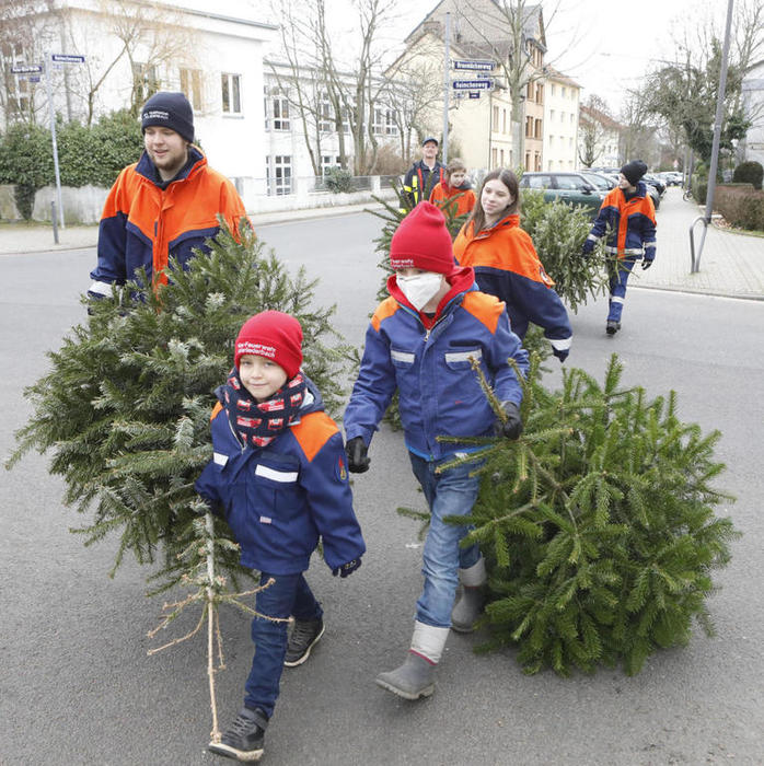Paul (7) geht stolz voran, Merlin (9) folgt auf dem Fuß: Die Mitglieder der Unterliederbacher Mini- und der Jugendfeuerwehr sammelten die abgeschmückten Christbäume ein und brachten sie zu Sammelplätzen im Stadtteil, von wo sie dann mit Traktor und Anhänger abgeholt wurden. FOTO: Maik Reuß
